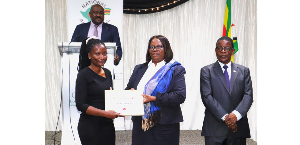 The Manica Post health reporter, Tendai Gukutikwa, receives her award from National Aids Council board chair, Mrs Nester Mukwewa, while NAC CEO, Dr Bernard Madzima looks-on