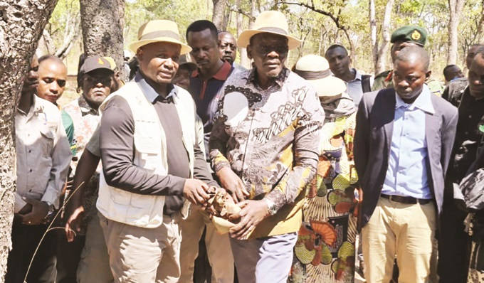 Vice President Kembo Mohadi (centre) and Institute of African Knowledge chief executive officer Ambassador Kwame Muzawazi (left foreground) hold a spent cartridge at one of the 11 mass graves at Mkushi Girls Training Camp where Zimbabwean freedom fighters lie buried in Zambia yesterday. Looking on are Zambian officials and members of the nearby community.— Picture: Africa Moyo