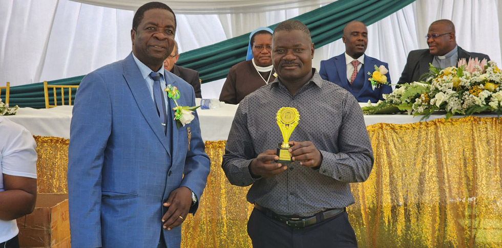St Joseph’s Primary School Rusape School Development Committee chairman, Mr Tapiwa Mashiri (right) displays a trophy they won