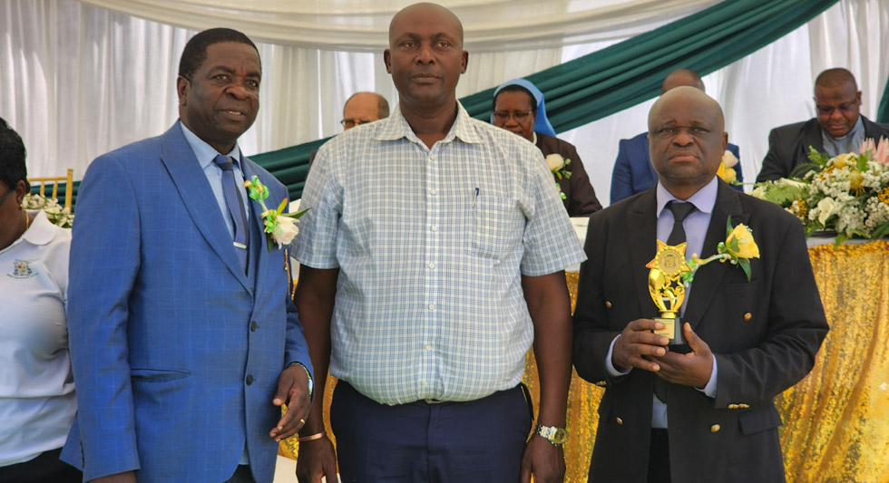 Manicaland Provincial Education Director, Mr Richard Gabaza (left) presents an award to St Columbus High School (Honde Valley) head, Mr Henry Nyazenga (right) and the SDC chairman, Mr Lovemore Mubaira