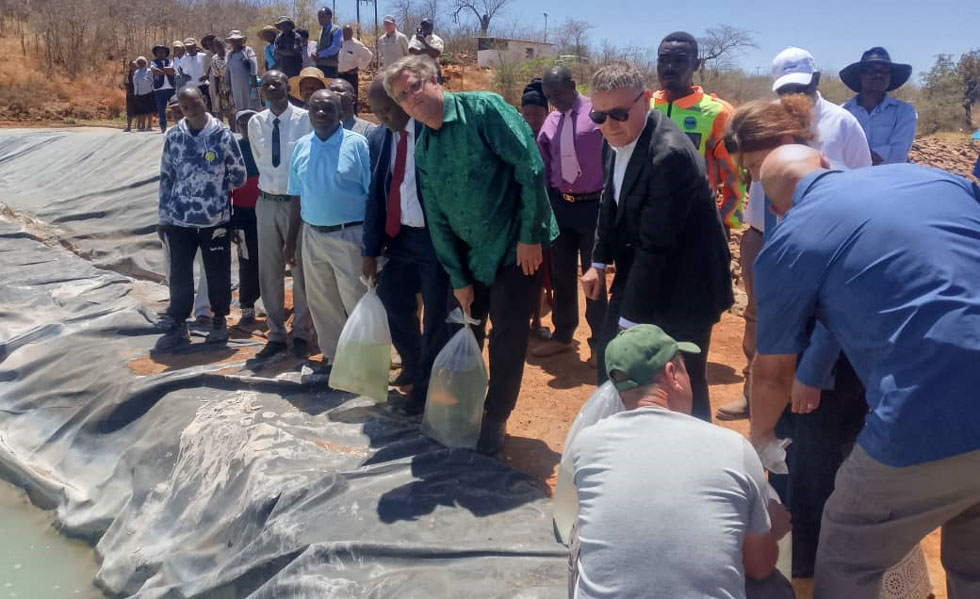 Transport and Infrastructural Development Deputy Minister, Honourable Joshua Sacco (in green shirt) and Alrosa MD, Mr Sergey Loshkarev plant fingerlings in the ponds