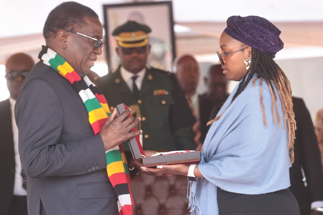 President Mnangagwa presents the national flag to Brig-Gen Mzheri's daughter