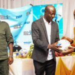 Guest of honour Benjani Mwaruwari (centre) presents a ball to an inmate while Bulawayo Metropolitan Zimbabwe Prisons and Correctional Services Officer Commanding Mkhulunyelwa Ngwenya looks on