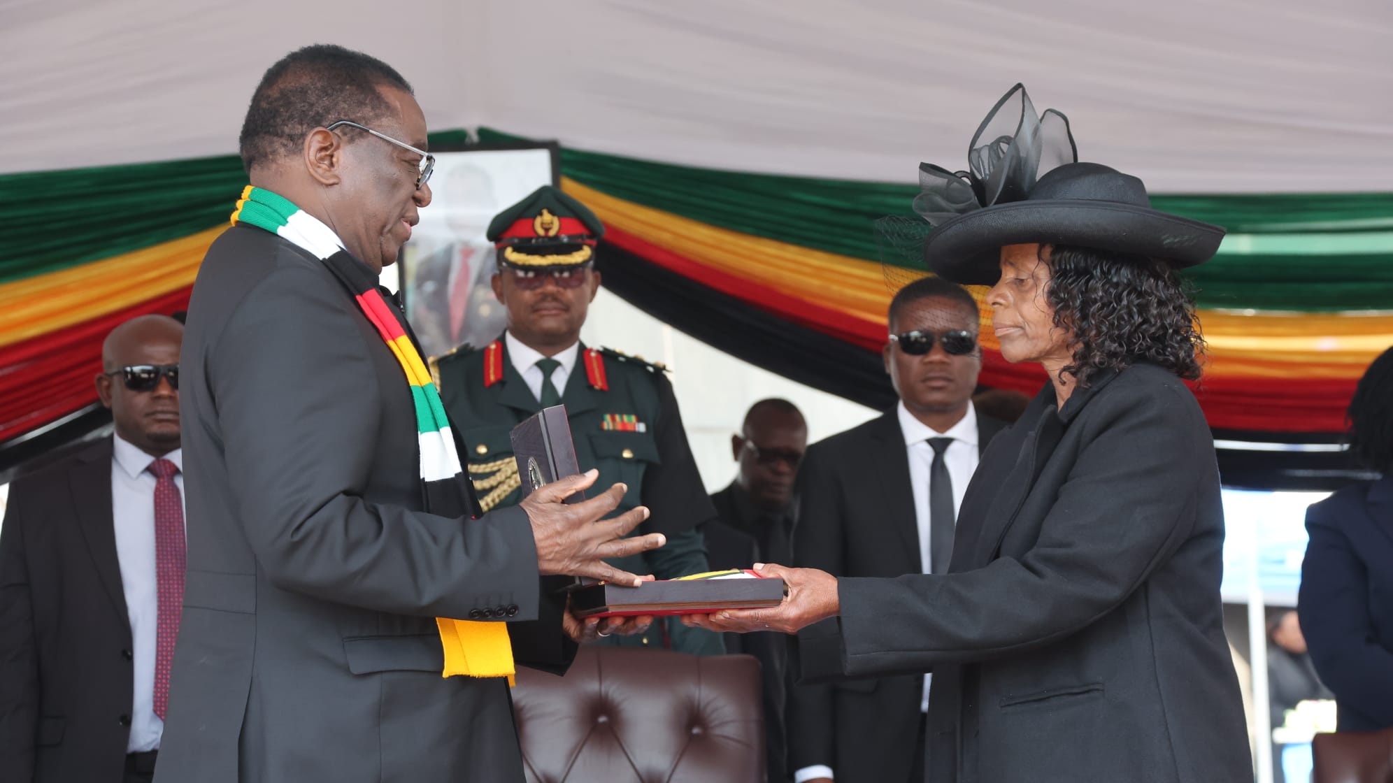 President Mnangagwa hands over the national flag to Ambassador Victor Matemadanda's widow