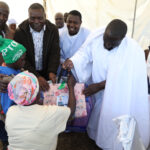 A mother receives the donation on behalf of her child from Madzibaba Deminase