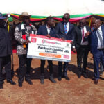 Minister of Youth Empowerment, Development and Vocational Training Honourable Tinomuda Machakaire (fifth from left) hands over a US$5 000 loan dummy cheque to Pardon Chishuri the Government and ruling ZANU PF officials look on at Magamba Training Center today