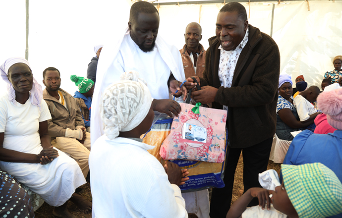 ZANU PF Mutare DCC chairman, Cde Tarwireyi Mabika hands over donations to a beneficiary’s parent as Madzibaba Deminase assists