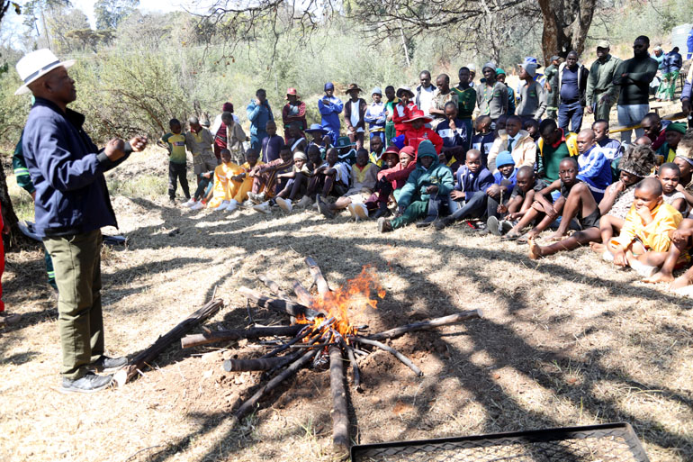 Chief Mutasa takes primary school boys through the traditional method of making a fire