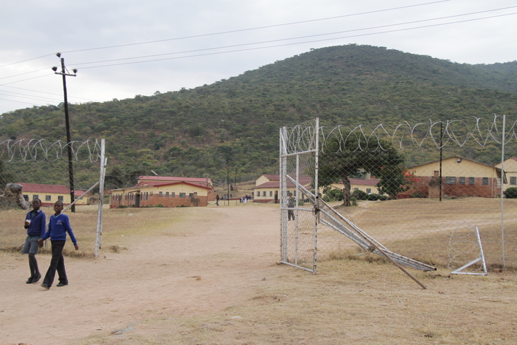 Two students walk past a gate damaged during the violent protests at Mutambara High School this week