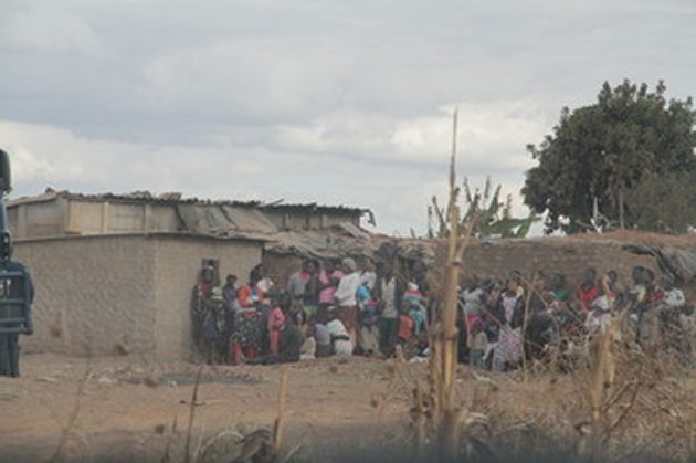 Willdale squatter compound dwellers in Mt Hampden stand near the aircraft accident scene where two Air Force of Zimbabwe officers perished