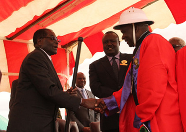 President Mugabe hands over the symbolic traditional stick to Mr Alfred Simba Tome, the newly-installed Chief Bepere in Zvimba yesterday while president of the Chief’s Council Chief Fortune Charumbira looks on. — — (Picture by Tawanda Mudimu)