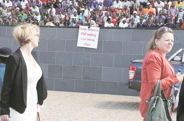 Dutch Ambassador to Zimbabwe Gera Sneller (right) walks past a poster inscribed with a message which denounces foreign meddling in Zimbabwe’s internal affairs