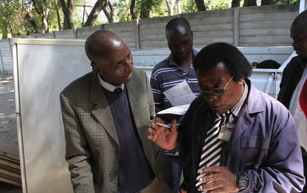 Former ZCTU president Lovemore Matombo(left) speaks to Deputy Messenger of Court Mr Farai Banga over the attachment of his property in Harare yesterday