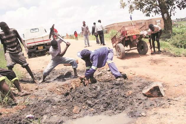 Workmen in Caledonia, Harare, dig a trench yesterday while constructing a makeshift bridge to allow people and vehicles to pass through. The area is rendered impassable during the rainy season. — Munyaradzi Chamalimba