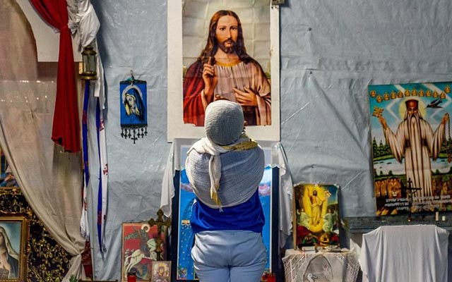 A refugee prays at the Jungle camp in Calais on Christmas Day 2015