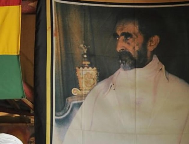 A Rastafarian stands next to a banner of Haile Selassie in Kingston, Jamaica