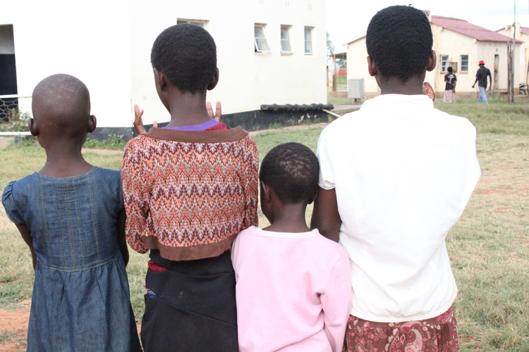 Precious Kurwa (right), a teen mother who is living with HIV stands with her siblings at the camp. She lost her medical records during the floods