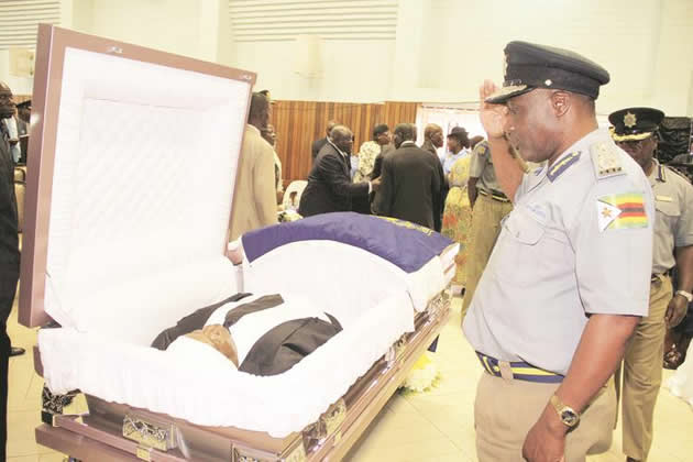 Police Deputy Commissioner-General Levie Sibanda salutes as he views the body of Senior Assistant Commissioner Shadreck Mubaiwa at a church service at Morris Depot in Harare yesterday