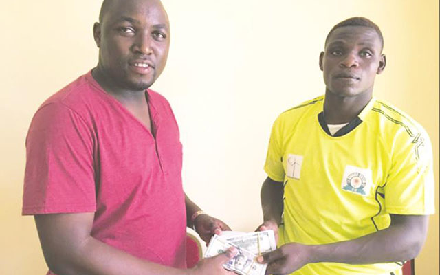 ALL ABOUT THE BENJAMINS . . . Zimbabwe international defender Elisha Muroiwa (right) is shown being handed the bills of cash by his agent in Tanza