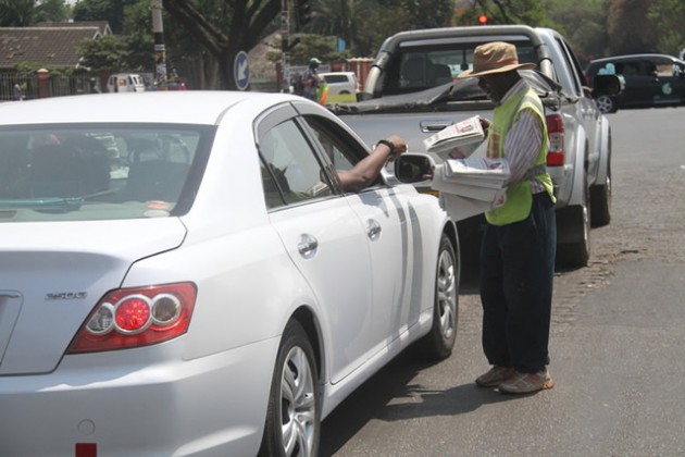 Mr Kavhumbura sells a copy of The Herald to a motorist  