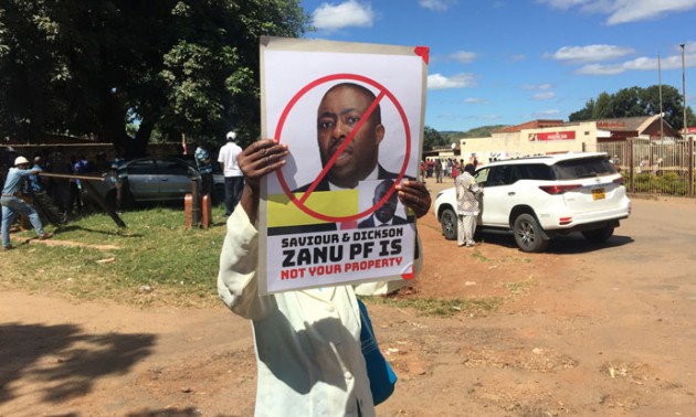 A protestor holds a banner aloft. Picture by Felex Share