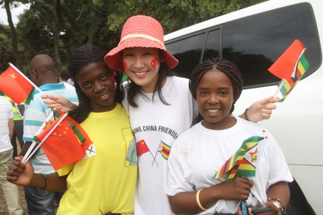 A Chinese national poses for a photo with two Zimbabwean teenagers