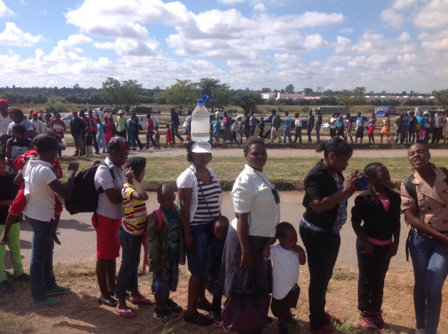 A woman in the queue carrying a 5-litre bottle of drinking water (Lloyd Gumbo)