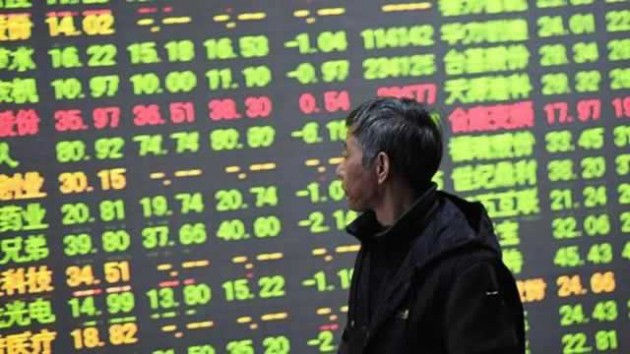 A passer-by looks at an electronic stock indicator