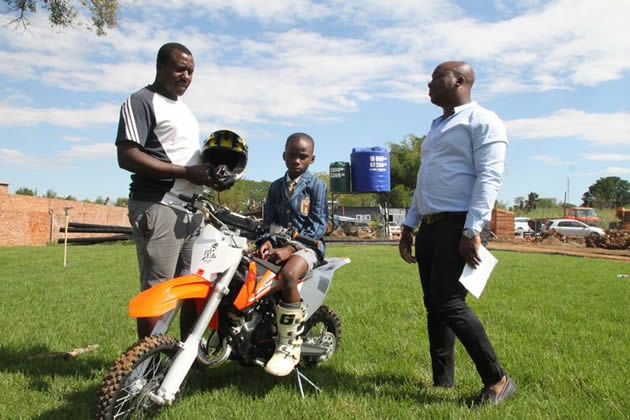 GOING PLACES . . . Promising Zimbabwean motocross rider Emmanuel Bako (centre) has a feel of his new machine while flanked by his father and manager Brighton (right) and trainer Stanley Mugiyo in Harare recently, as he prepares to race in major international races in Europe and South Africa next year