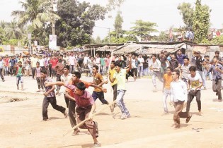 Bangladesh garment workers throw stones at police during a protest in Gazipur 40 km north of Dhaka yesterday. Angry Bangladesh garment workers blocked roads, set factories alight and clashed with police for a third day as protests demanding a minimum monthly wage of US$100 spread outside the capital Dhaka. — AFP