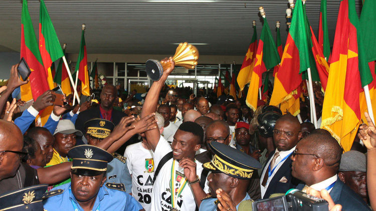 THE HEROES ARE BACK IN TOWN . . . Captain Benjamin Moukandjou (ABOVE) proudly holds the Nations Cup trophy as he makes his way past an excited crowd on arrival back in Yaounde this week.