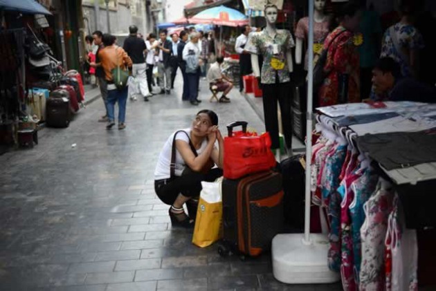 A woman looks on as she squats in front of a clothing shop in Beijing yesterday. Chinese inflation slowed to 2,6 percent year-on-year in August. - AFP