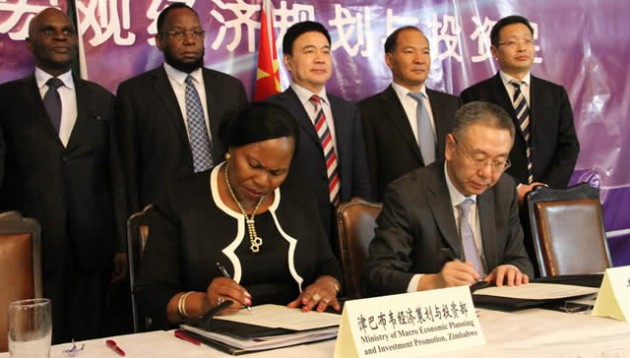 Macro-Economic Planning and Investment Promotion Deputy Minister Monica Mutsvangwa (left) and the Deputy Director General of Qingdao Bureau of Commerce Mr Chunyu Xianli (right) sign a MoU for economic co-operation yesterday while officials from both countries look on. — (Picture by Innocent Makawa)