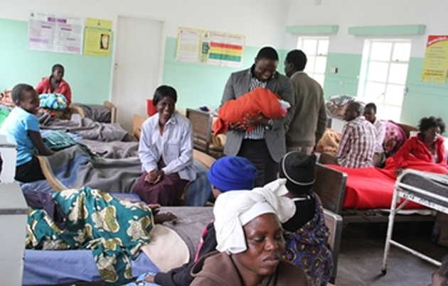 Mazowe West legislator Cde Ray Kazembe holds a newly born baby during his tour of a congested women's ward at Concession Hospital on Tuesday.
