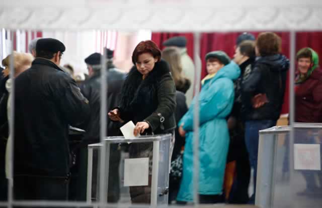 A woman is reflected in a mirror as she casts her ballot during voting in a referendum at a polling station in Simferopol March 16, 2014. – Reuters.