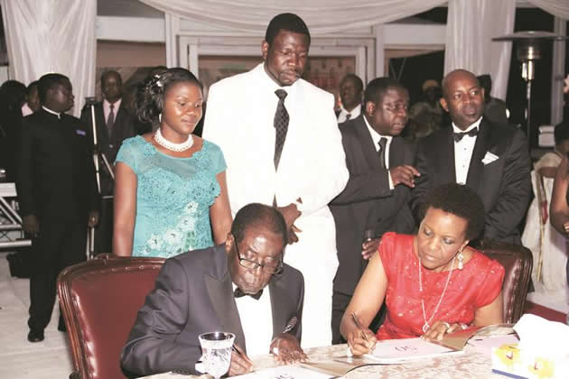 President Mugabe and First Lady Amai Grace Mugabe sign the pictorial biography of the First Lady while Prophetic Healing and Deliverance Ministries leader Prophet Walter Magaya (second from left), his wife Tendai (left) and chairperson of the organising committee for the First Lady's birthday and fundraising dinner Mr Rodney Dangarembizi (extreme right) look on in Harare over the weekend