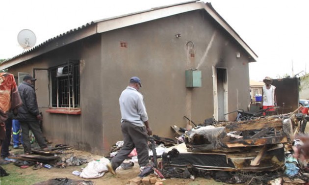 People gather at the allegedly petrol-bombed house at Mbuya Nehanda Housing Cooperative in Dzivaresekwa, Harare, yesterday