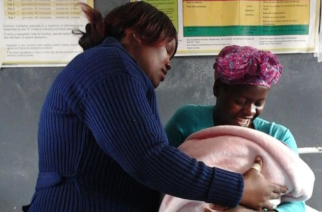 A nurse helps Fortune Mudisi, who had given birth at Phalapala clinic, nurse her baby