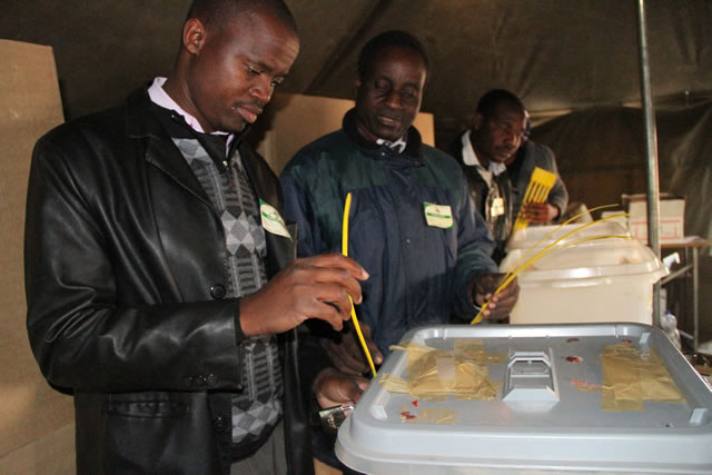 A polling officer seals a ballot box for presidential candidates under a watchful eye of ZEC presiding officer Clever Mutsigiri at Murambinda shoopping centre polling station.
