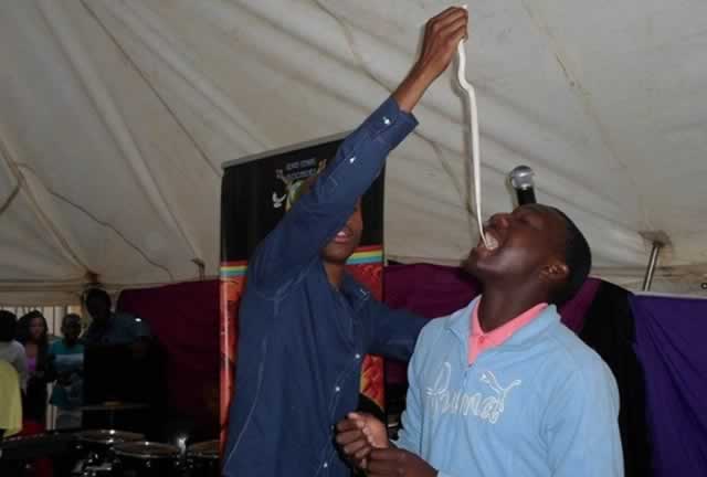 STUNT OR MIRACLE . . . A “prophet” feeds a follower a snake