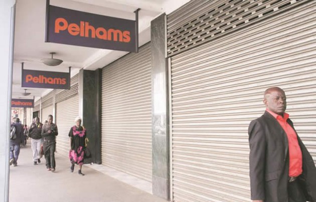 PEOPLE PASS BY A CLOSED PELHAMS SHOPS IN HARARE YESTERDAY   (1)