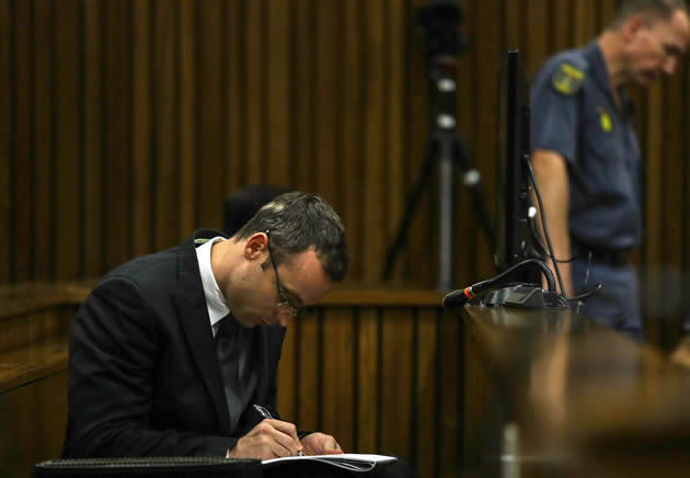 South African Paralympic athlete Oscar Pistorius writes during his murder trial at the North Gauteng High Court in Pretoria on March 11, 2014. – AFP.