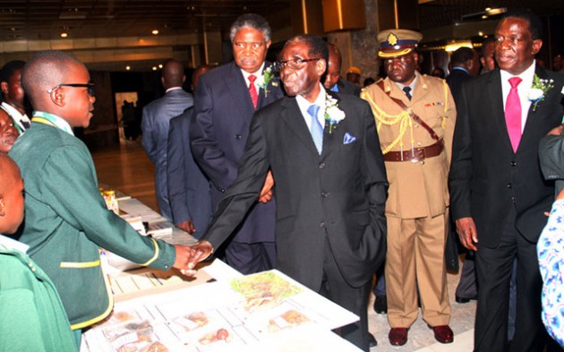 President Mugabe greets Munashe Munzwadi of Chigwedere Primary School, Hwedza, during the official opening of the 11th Zimbabwe Research Symposium in Harare yesterday. Looking on are Vice Presidents Emmerson Mnangagwa and Phelekezela Mphoko. - Picture by John Manzongo