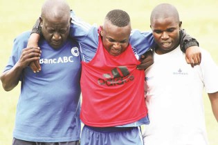 INJURY SCARE . . . Dynamos new signing, Tafadzwa Rusike (centre), is helped off the training pitch by club vice-chairman, David Mandigora (left), who is aiding with the coaching duties, and physiotherapist Knowledge Zambo at Raylton yesterday. — Picture by William Mafunga