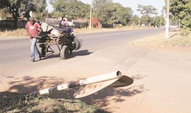 A recycling merchant pulls his cart along a nameless street in one of Harare’s older suburbs