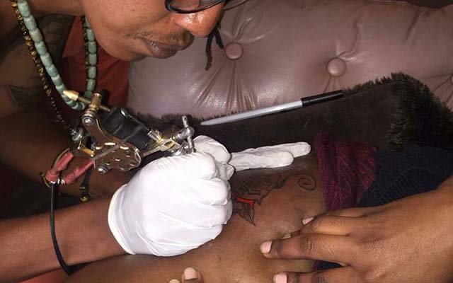 Craig of Mystic Tattoos inscribing an image on a woman's leg