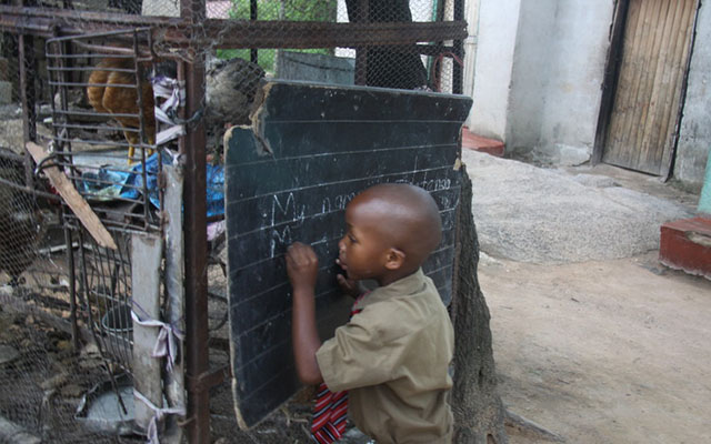 Tinotenda Manyemba writes on his practice chalkboard — Pictures by  Memory Mangombe