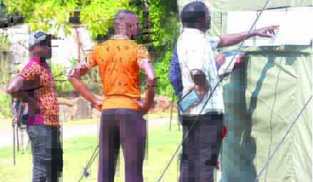 Prospective voters check their names on the voters roll at the Chimanimani Magistrates’ Court Tent last week