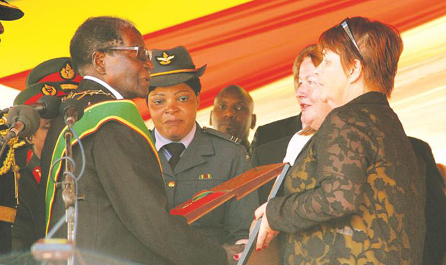 Head of State and Government and Commander-in-Chief of the Zimbabwe Defence Forces President Mugabe posthumously bestows the Royal Order of Munhumutapa on Father Paschal Slevin, an Irish missionary, who contributed immensely to the liberation of Zimbabwe. On hand to receive the award were Fr Slevin’s nieces Frances Slevin Doran (black and orange dress) and Geraldine Slevin Keogh, during the Zimbabwe Defence Forces Day celebration at the National Sports Stadium in Harare yesterday. — (Picture by Tawanda Mudimu)
