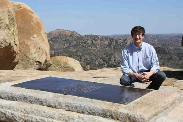 A tourist poses next to Cecil John Rhodes’ grave in the Matopos